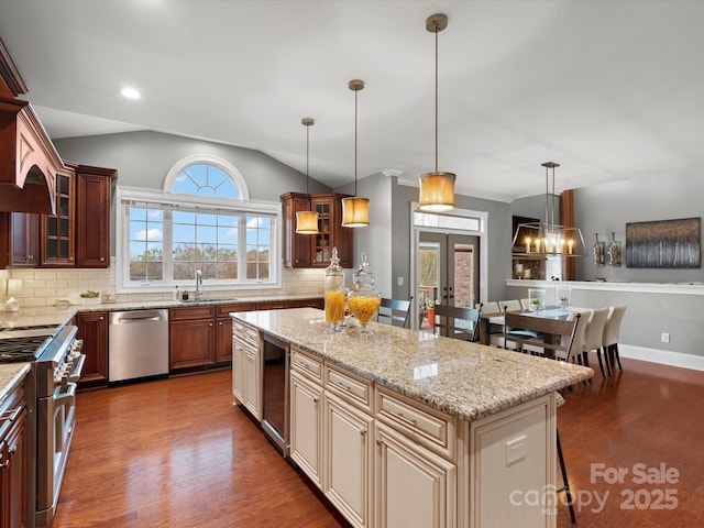kitchen with dark wood-type flooring, a center island, appliances with stainless steel finishes, and lofted ceiling