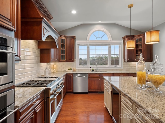 kitchen featuring glass insert cabinets, vaulted ceiling, appliances with stainless steel finishes, dark wood-style flooring, and a sink