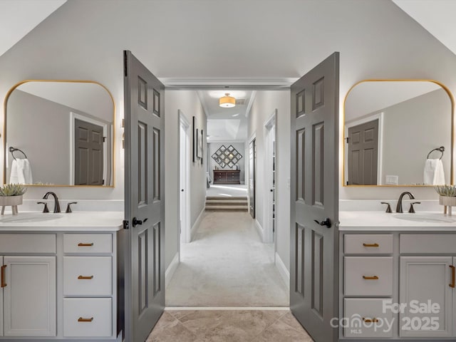 bathroom featuring two vanities, a sink, and baseboards