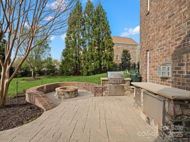 view of patio featuring an outdoor kitchen, a fire pit, fence, and area for grilling
