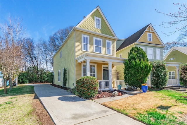 view of front of house with a porch, a front yard, and driveway