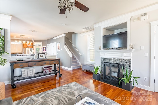 living room featuring visible vents, baseboards, stairway, wood finished floors, and a fireplace