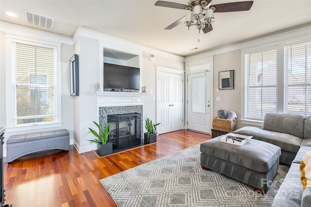 living room with a fireplace, visible vents, a wealth of natural light, and wood finished floors