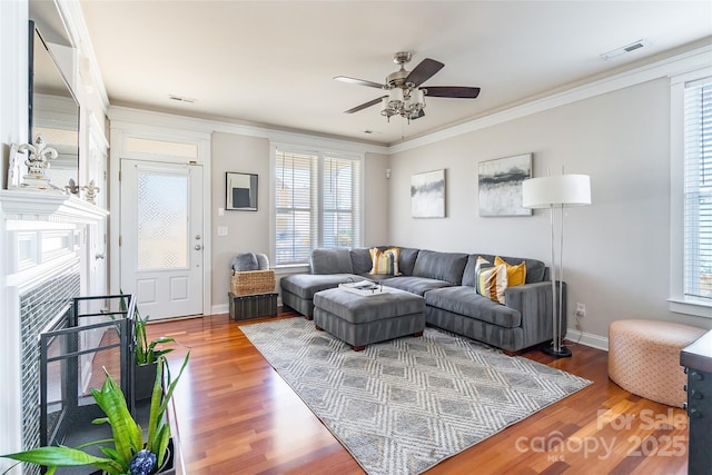 living area featuring ornamental molding, visible vents, and wood finished floors