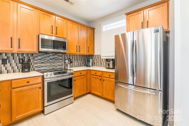 kitchen featuring tasteful backsplash, stainless steel appliances, and light countertops