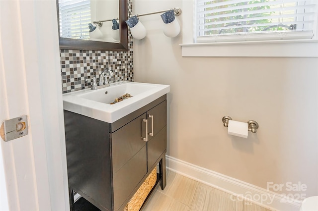 half bathroom featuring plenty of natural light, tasteful backsplash, baseboards, and vanity