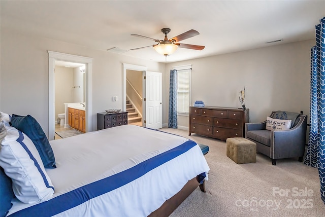 bedroom featuring ensuite bathroom, light colored carpet, a ceiling fan, baseboards, and visible vents