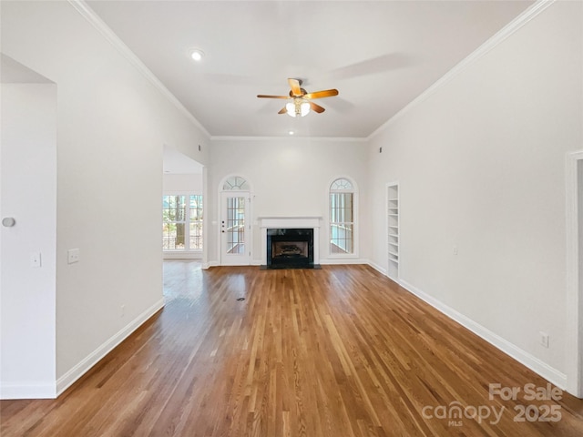 unfurnished living room with baseboards, built in features, light wood-style flooring, and a fireplace with flush hearth