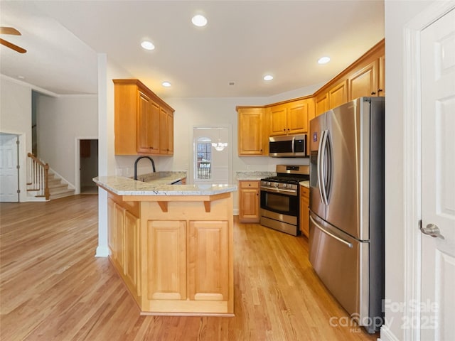 kitchen with recessed lighting, a peninsula, a breakfast bar, light wood-style floors, and appliances with stainless steel finishes