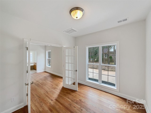 spare room featuring french doors, wood finished floors, visible vents, and baseboards