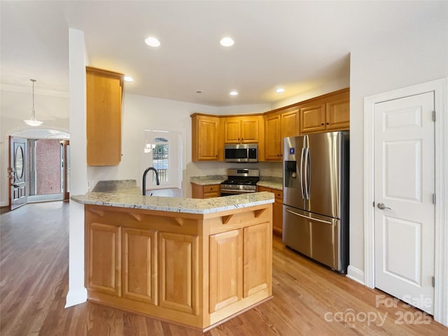 kitchen featuring light wood-style flooring, appliances with stainless steel finishes, a peninsula, a sink, and recessed lighting