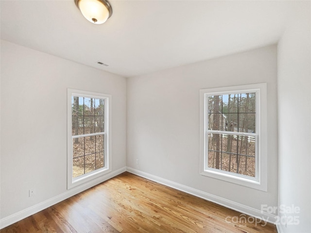 spare room featuring visible vents, baseboards, and wood finished floors