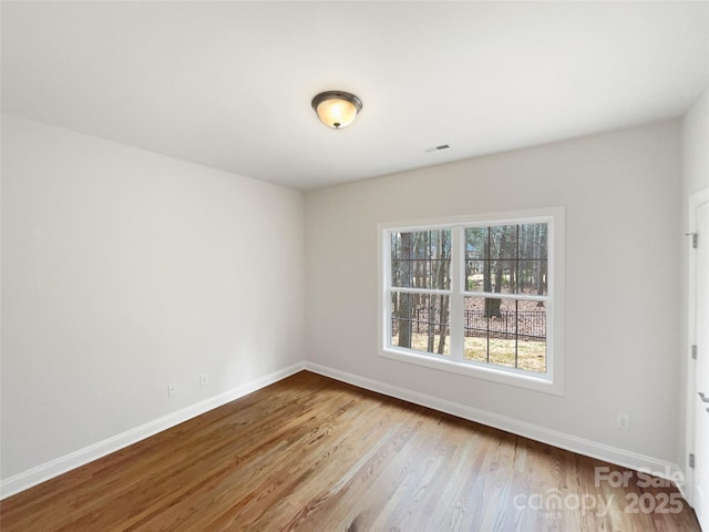 spare room with visible vents, baseboards, and wood finished floors