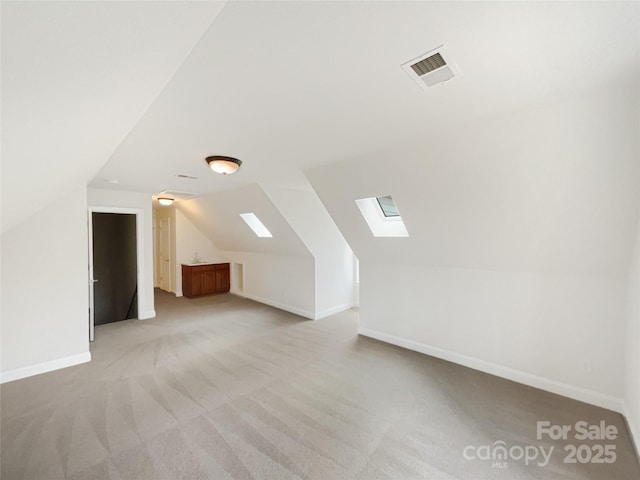 bonus room with light carpet, lofted ceiling with skylight, visible vents, and baseboards