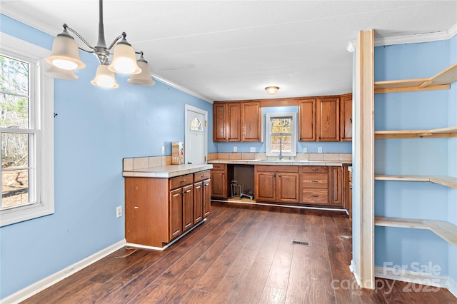 kitchen with dark wood-type flooring, brown cabinets, and ornamental molding