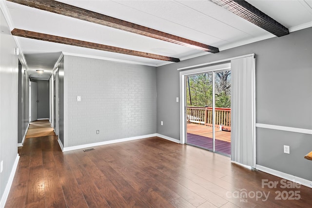 unfurnished room with brick wall, beam ceiling, baseboards, and wood finished floors