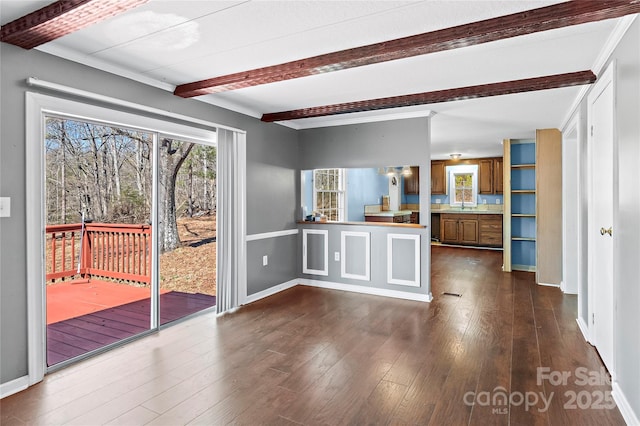 kitchen featuring baseboards, brown cabinetry, dark wood finished floors, and beamed ceiling