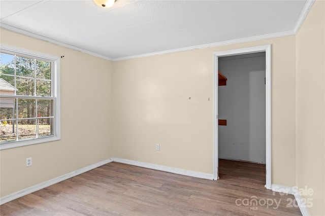 unfurnished room with baseboards, wood finished floors, and crown molding