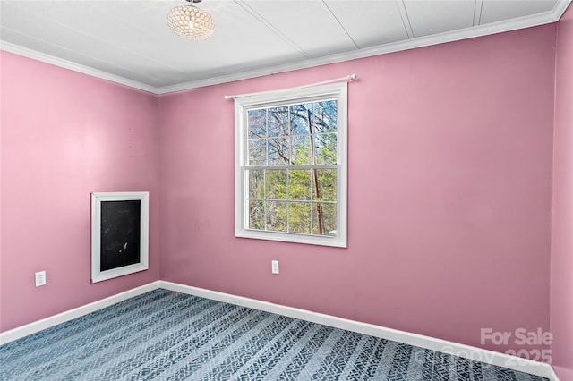 carpeted empty room featuring baseboards and crown molding