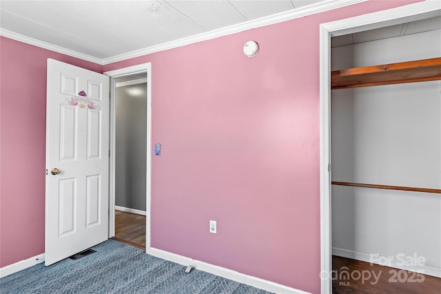 unfurnished bedroom featuring baseboards, dark colored carpet, and crown molding