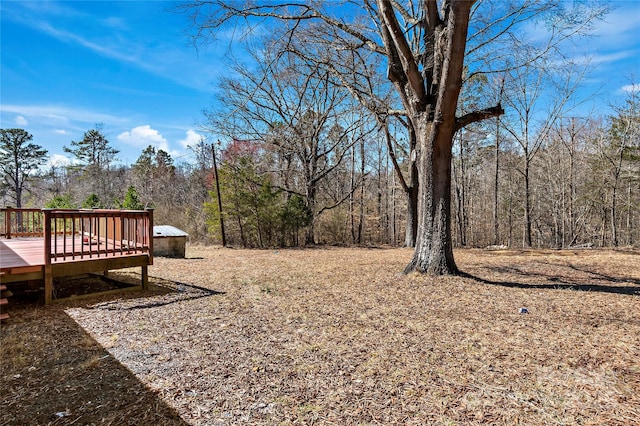 view of yard featuring a deck and a wooded view