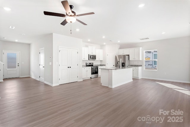 kitchen with light wood-style flooring, recessed lighting, white cabinetry, open floor plan, and appliances with stainless steel finishes