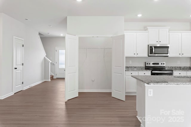 kitchen featuring stainless steel appliances, recessed lighting, white cabinets, light stone countertops, and light wood-type flooring