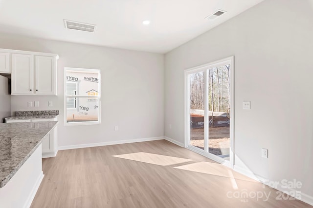 unfurnished dining area with baseboards, visible vents, and light wood finished floors