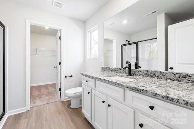 full bath featuring toilet, visible vents, wood finished floors, and vanity