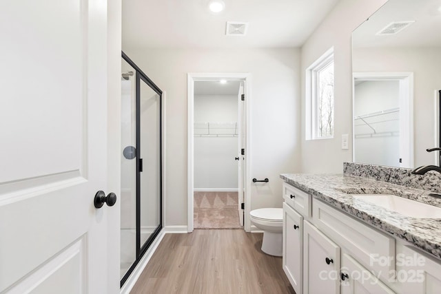 bathroom featuring toilet, a stall shower, and visible vents