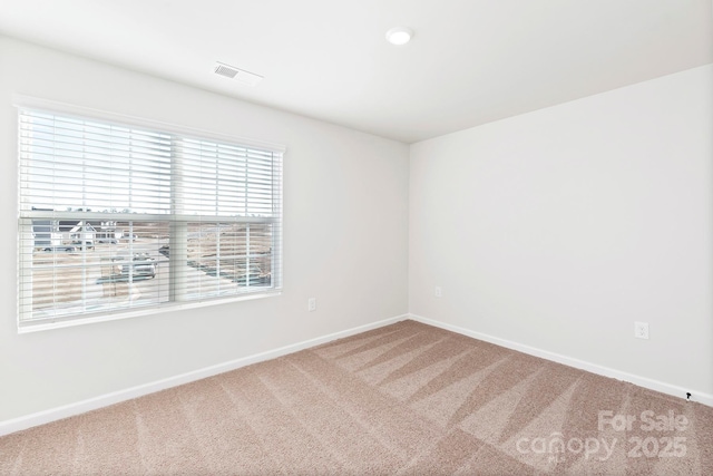 spare room with carpet, visible vents, and baseboards