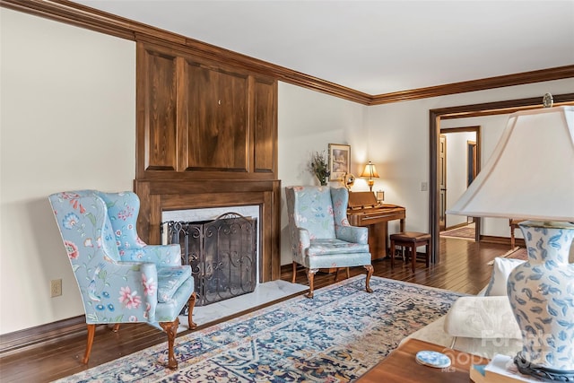 living area with ornamental molding, a high end fireplace, and hardwood / wood-style flooring