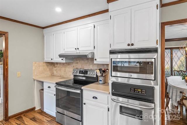 kitchen featuring under cabinet range hood, tasteful backsplash, appliances with stainless steel finishes, and light countertops