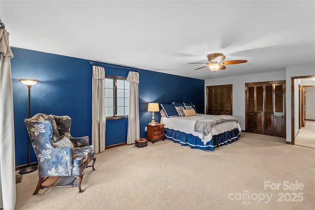 bedroom featuring carpet floors, ceiling fan, and two closets