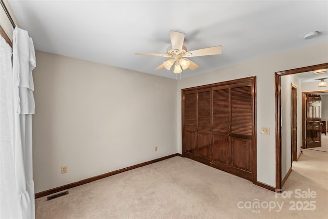 unfurnished bedroom with baseboards, visible vents, a closet, and light colored carpet