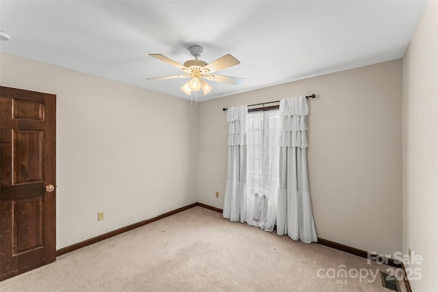 empty room featuring a ceiling fan, light carpet, and baseboards