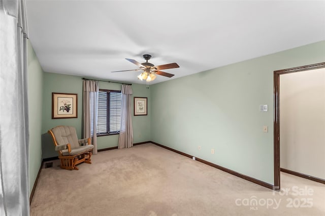 sitting room with baseboards, ceiling fan, and light colored carpet