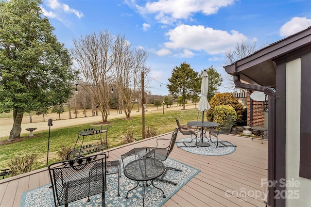 deck with outdoor dining area and a yard