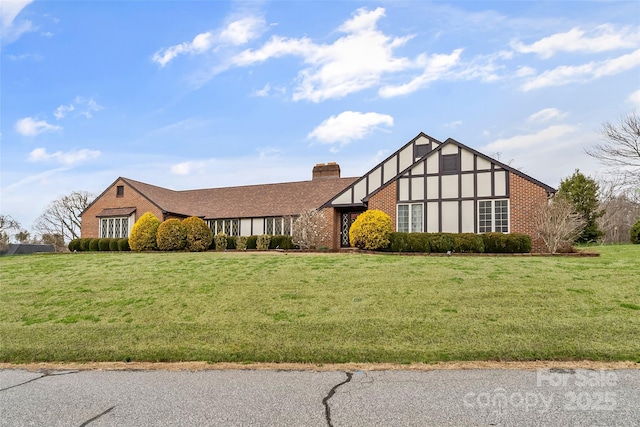 view of front of home with brick siding, a chimney, and a front yard