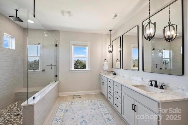 full bathroom with double vanity, a sink, a chandelier, and a tile shower