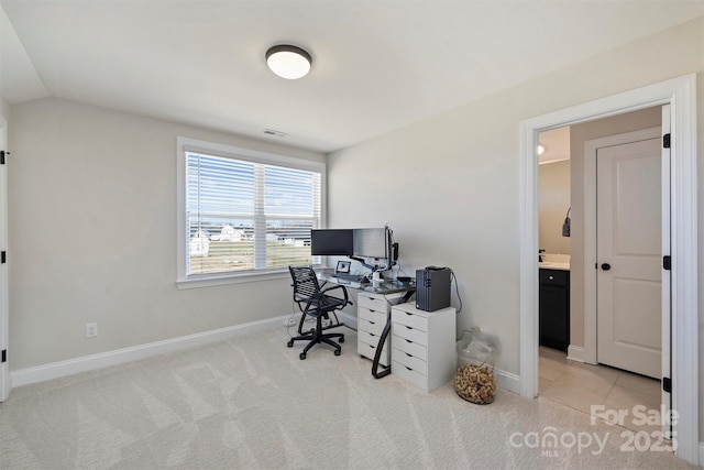 office area with baseboards, lofted ceiling, visible vents, and light carpet