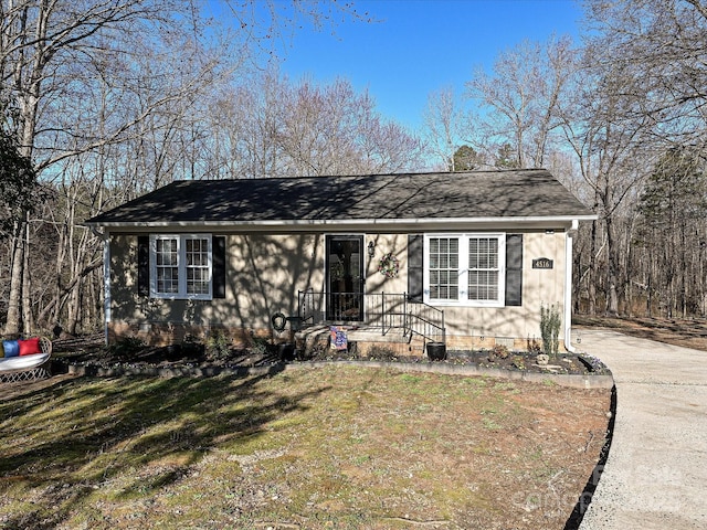 ranch-style house featuring driveway and a front lawn