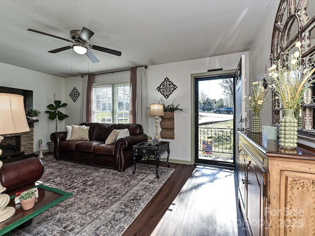 living area with baseboards, a textured ceiling, wood finished floors, and a ceiling fan