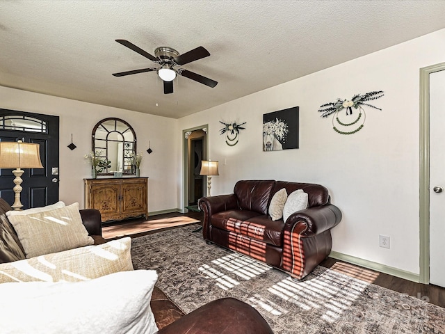 living room with baseboards, a textured ceiling, ceiling fan, and wood finished floors