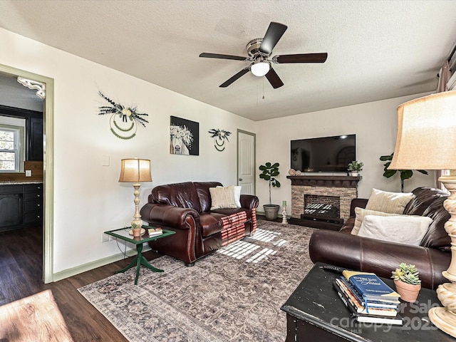 living area with a fireplace, a textured ceiling, and wood finished floors