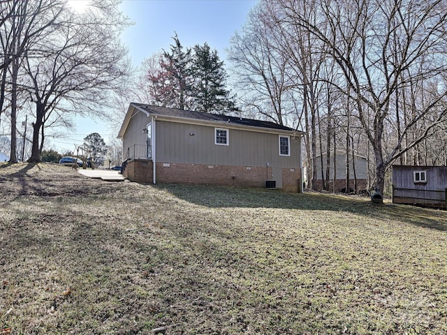 back of house featuring crawl space and a lawn