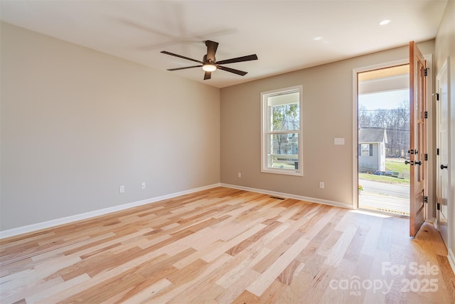 spare room featuring light wood finished floors, visible vents, a ceiling fan, and baseboards