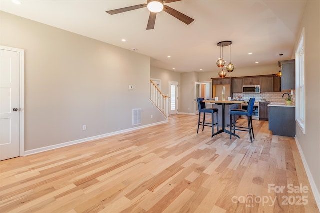 kitchen with visible vents, a center island, a breakfast bar area, light countertops, and appliances with stainless steel finishes