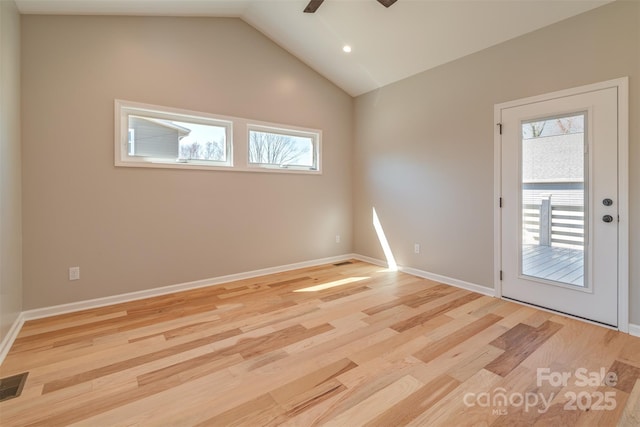 spare room with a wealth of natural light, light wood finished floors, and lofted ceiling