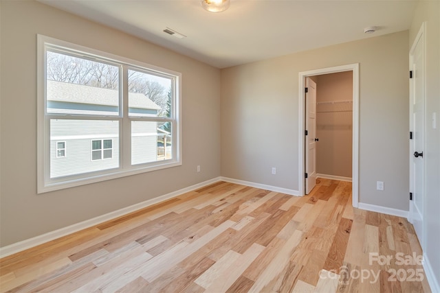 unfurnished room with visible vents, light wood-style floors, and baseboards